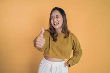 smiling young woman stand with thumbs up on isolated background