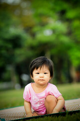 Cute baby Thai girl feel happy and relaxing , sitting on the grass in the park