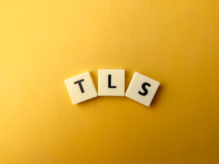 Top view word toys with text TLS (Transport Layer Security) on yellow background.