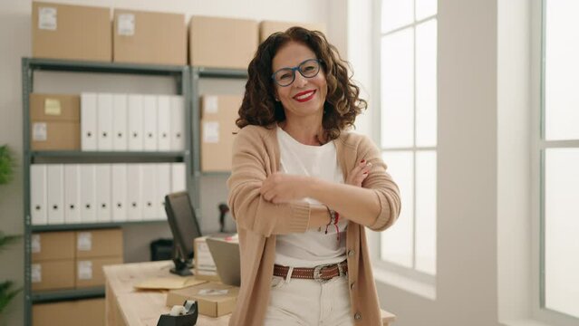 Middle age woman ecommerce business worker standing with arms crossed gesture at office