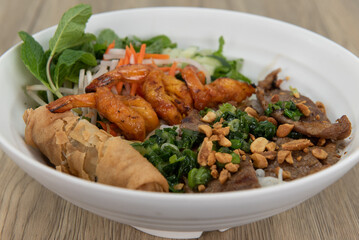 Generous bowl of vermicelli salad, full of shrimp, beef, and egg roll for a Vietnamese meal