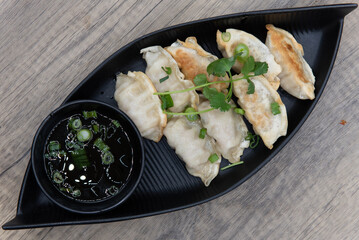 Overhead view of crispy pot sticker dumplings for a Vietnamese meal appetizer served in a boat