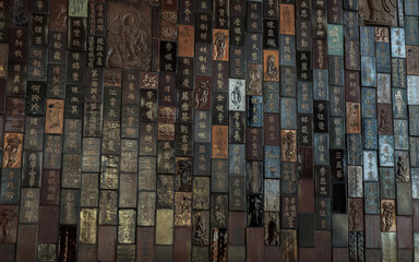 Bangkok, Thailand - Feb 19, 2022 : Chinese lettering teachings and Carved buddha images into a slab of colored tiles on temple wall of Fo Guang San Temple. No focus, specifically.