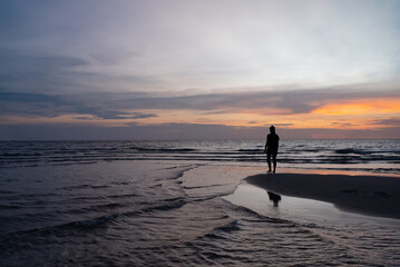 Silhouette of Woman Stanidng on Beach at Sunset