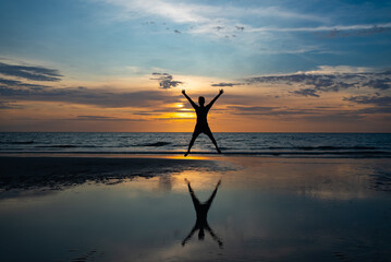 Silhouette of man Jumping on Beach at Sunset