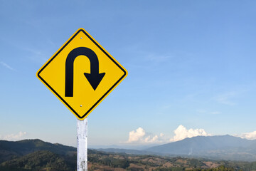 Traffic sign: Right U-turn sign on cement pole beside the rural road with white cloudy bluesky...