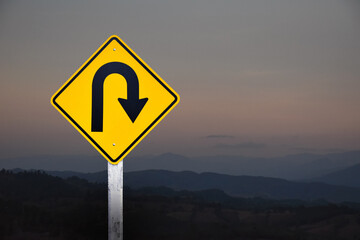 Traffic sign: Right U-turn sign on cement pole beside the rural road with white cloudy bluesky background, copy space.