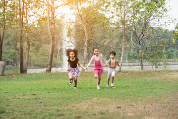 Small group of a happy children run through the park in the background of grass and trees. Children's outdoor games, vacations, weekend, Children's Day