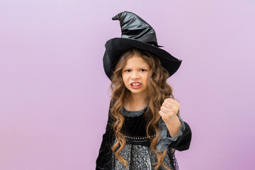 A very surprised little witch on a purple isolated background. A child in a sorcerer's costume for Halloween