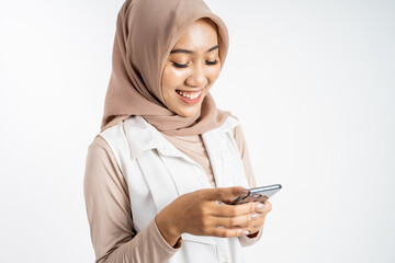 asian woman in hijab smiling while using a cell phone