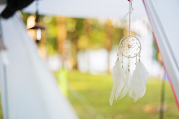 dream catcher with white feather or wind chime hanging on camping cabin tent for movement from wind...