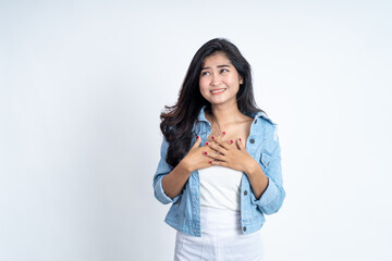young woman holding chest while feeling happy on isolated background