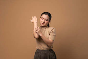 Asian woman was sick with irritate itching her skin standing isolated on beige background.