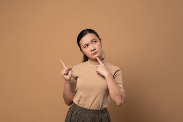 Asian woman feel confuse, standing isolated on beige background.
