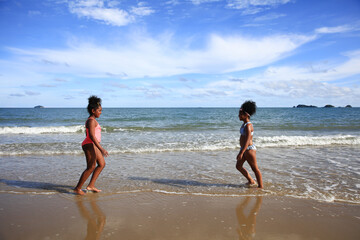 Two sisters runing on the tropical beach on summer vacation