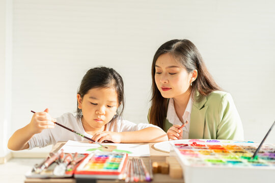 cute little children painting color, learn with teacher in education classroom with copy space, select focus at child. asian beautiful children happy and fun color painting education in small school