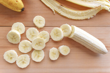 Banana slices on a bamboo cutting board.  Flat lay top view photo.  Food from above.