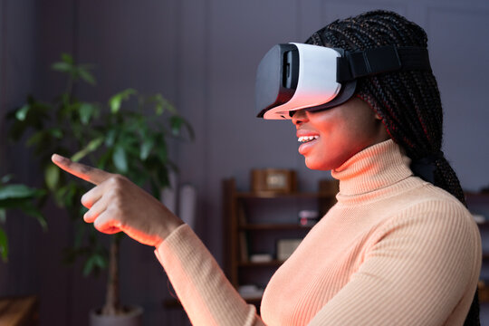 Young black woman wearing vr glasses touch objects in virtual world. Female using goggles mobile application for innovative education, shopping in 3d store, interacting with digital headset interface