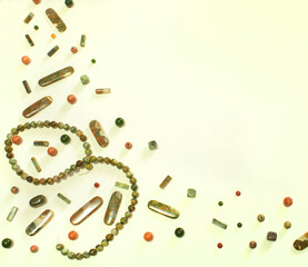 Orange and Green Semiprecious Gemstone Beads on Cream Background with Copy Space in Top Down Shot Corner Fill for Sale Sign or Inspiration Board
