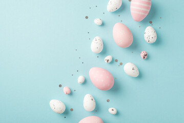 Top view photo of easter decorations glowing confetti pink and white easter eggs on isolated pastel blue background with copyspace