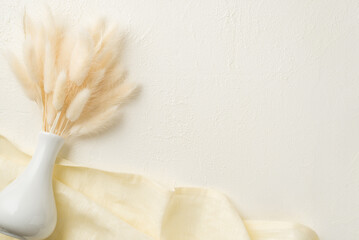 Top view photo of white vase with bunch of lagurus flowers and linen on isolated white background...