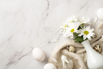 Top view photo of the white vase with few daisies three eggs and two quail ones on the textured textile on isolated marble background copyspace