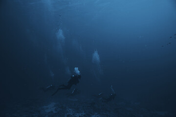 Obraz na płótnie Canvas divers underwater at depth in the blue sea background