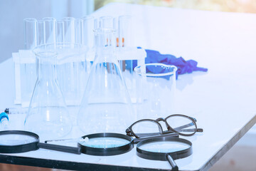 Beaker glove and test tube for testing chemical reaction on white table.