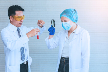 Scientist team in uniform holding beaker and test tube have chemical liquid for testing chemical reaction.