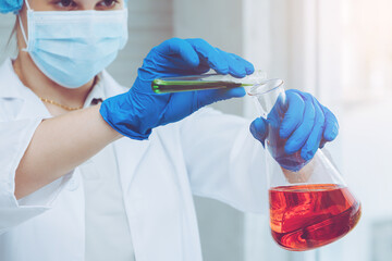 Scientist in uniform holding beaker and test tube have chemical liquid for testing chemical reaction.