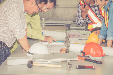 Craftsman tool with helmet and plan put on workplace table at construction site.