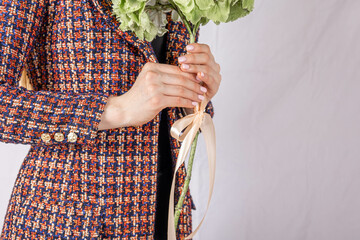 Close-up of woman's hand on tweed jacket holding flower. High quality photo