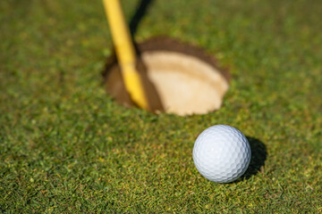 Close up of golf ball next to hole.