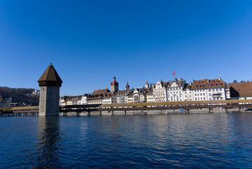 Fototapeta premium Medieval old town of Luzern with famous covered wooden Chapel Bridge (German: Kapellbrücke) and stone water tower on a sunny winter day. Photo taken February 9th, 2022, Lucerne, Switzerland.