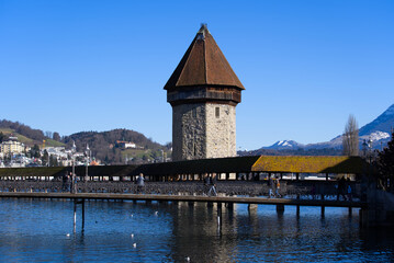 Medieval old town of Luzern with famous covered wooden Chapel Bridge (German: Kapellbrücke) and stone water tower on a sunny winter day. Photo taken February 9th, 2022, Lucerne, Switzerland.