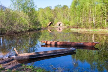 Log boats in a lake with some grass hut on the beach - obrazy, fototapety, plakaty