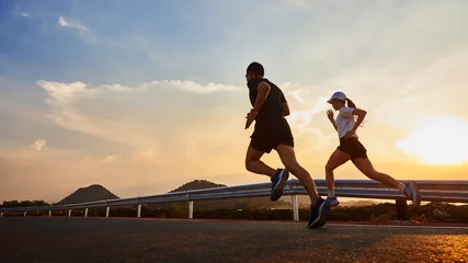 Selbstklebende Fototapeten Two people running at sunset. © JuYochi