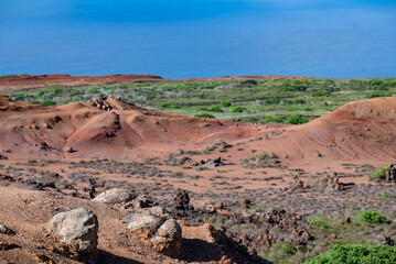 A view across a dry landscape, covered with lava rock, in the Garden of the Gods on Lanai, shows a vista of blue ocean and sky.