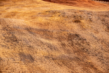 A close up of dry dirt road, tire tracks showing, dust and hillocks in red clay dirt makes an interesting background texture. 