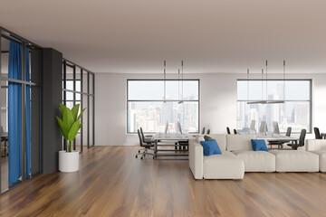 Modern office room interior, desktop computers on table, white walls. Hardwood floor. Panoramic city view windows. New empty couch with blue pillows. Concept of international coworking. 3d rendering