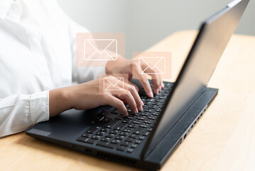 Woman hand typing on keyboard concept of receive or send email icon on working desk with laptop