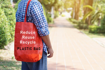 Man holds red bag with text  Reduce Reuse Recycle plastic bag. stands at the park. Concept :...