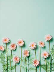 Pink marigold flowers and fresh leaves in a row on pastel green background. Creative floral spring...