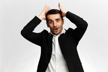portraits of a man in a black business suit with a surprised expression straightens his hair on a white studio background, copy space