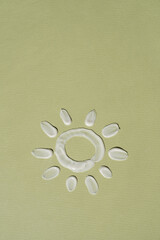 Fototapeta na wymiar Beauty product. Sun made of white cosmetic cream smear, smudge on neutral green background