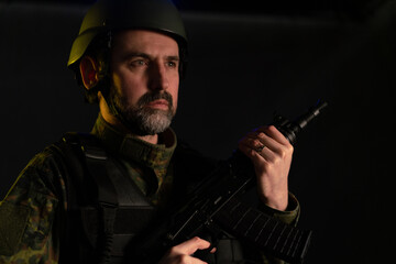 A soldier in military uniform and helmet with weapon on black background.