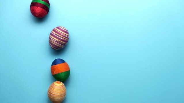 Colorful easter egg made from threads isolated on blue background. Easter concept.