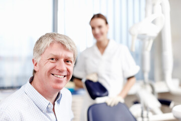 Obraz premium Smiling doctor with assistant. Portrait of handsome dentist smiling with his assistant in office.