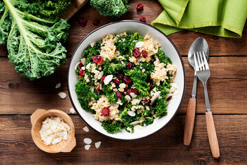 Fresh healthy salad with kale leaves, almond flakes, dried cranberry and quinoa. top view
