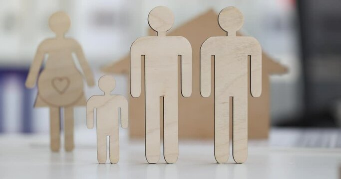 Wooden figurines of men and a pregnant woman closeup